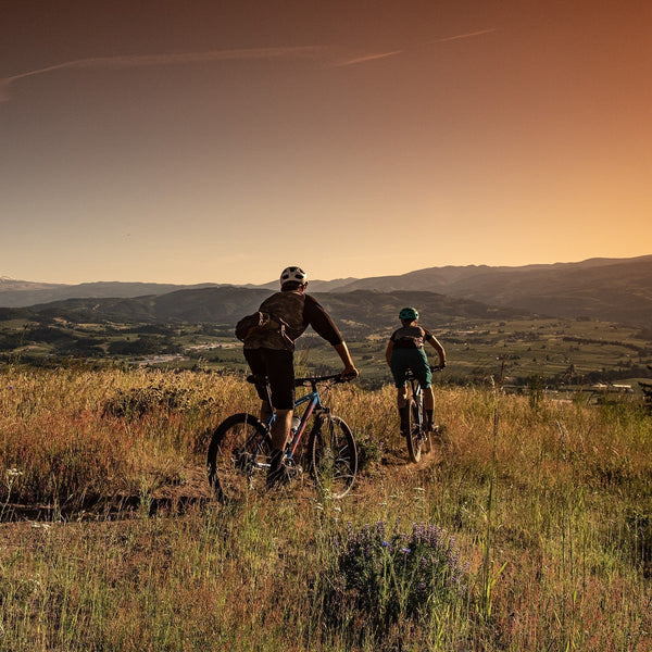 Two people riding their bikes during a sunset.